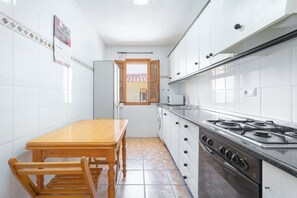 Uma cozinha com uma mesa de madeira, um fogão e uma janela.
