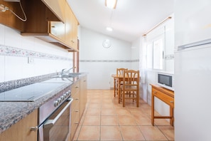 Una cocina con estufa, horno, microondas y sillas de madera.