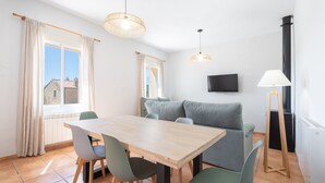 Un espace repas comprenant une table, des chaises, un canapé et un téléviseur fixé au mur.