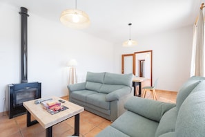 Una sala de estar con sofá, una mesa con libros, chimenea y lámparas colgantes.