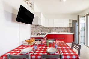 Een koelkast, een oven, een kookplaat, kookgerei, borden en bestek