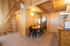 Un interno in legno con un tavolo da pranzo e sedie, una scala e un angolo cucina.
