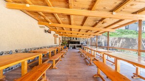 A covered outdoor dining area with wooden benches and a stone wall. - Caravan 'Bungalow 2' with Mountain View, Wi-Fi and Air Conditioning (Alós de Balaguer)