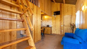 A wooden interior with a staircase, a kitchen area, and a blue sofa. - Caravan 'Bungalow 2' with Mountain View, Wi-Fi and Air Conditioning (Alós de Balaguer)