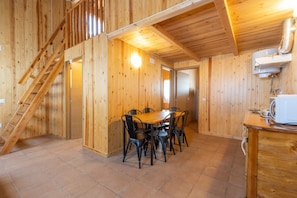 Un interior de madera con una mesa de comedor y sillas, una escalera y una zona de cocina.