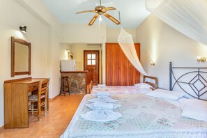 A bedroom with a bed, desk, chair, and a ceiling fan.