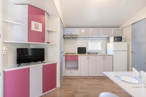 A compact kitchen with a flat-screen TV, microwave, and gas stove.