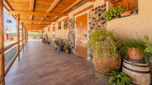 A covered corridor with wooden beams, stone walls, and potted plants.