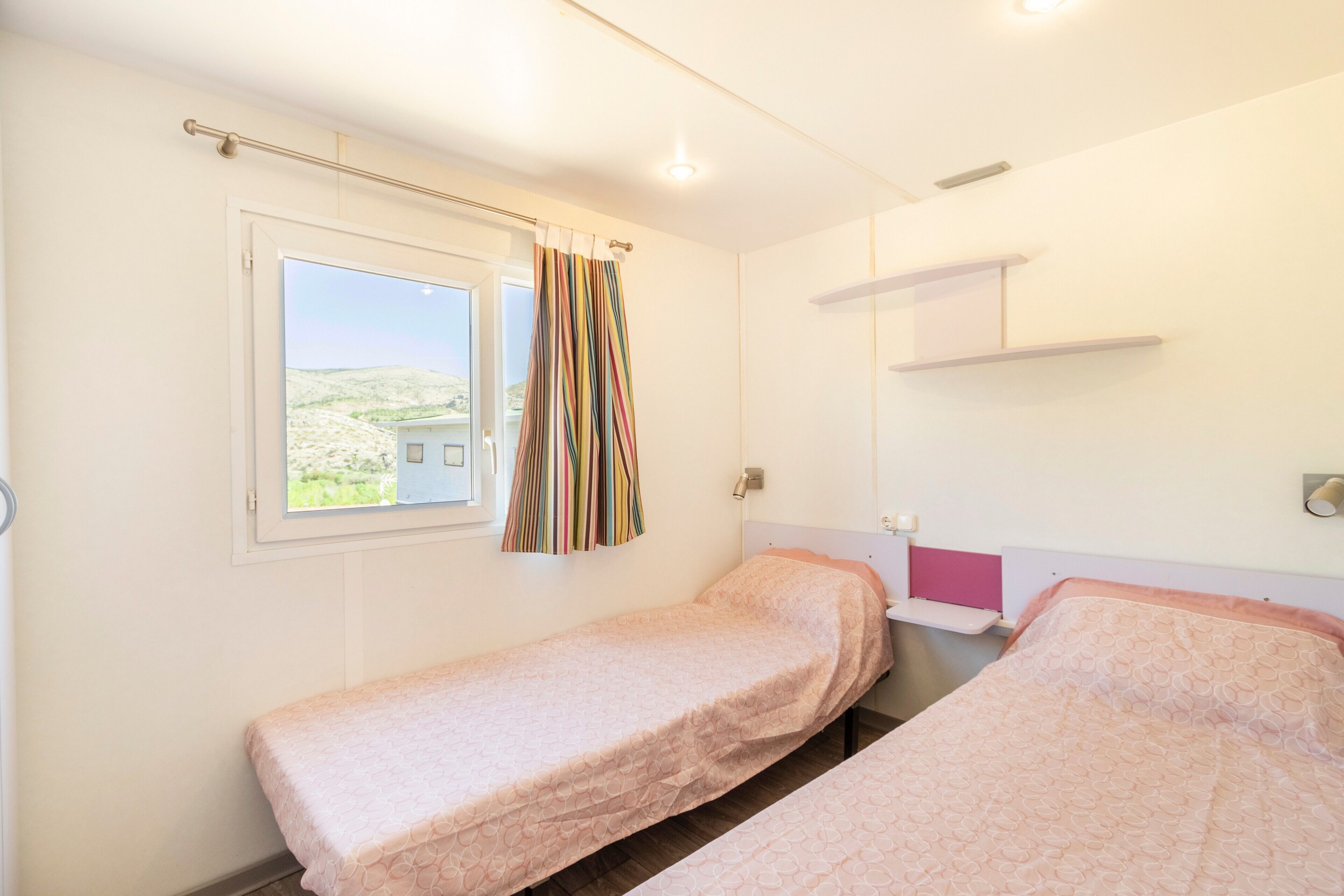 Ein Schlafzimmer mit zwei Betten, einem Fenster und Blick auf ein Haus.