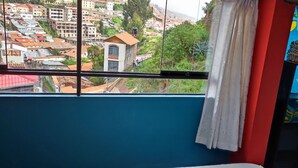 A room with a large window overlooking a densely built-up area with various buildings and greenery. - 10 minutes walking to the Cusco Main square  (Cusco)