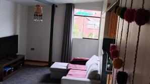 A living room with a sofa, a television, a window with curtains, and a hanging decoration. - 10 minutes walking to the Cusco Main square  (Cusco)