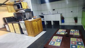 A kitchen with wooden cabinets, a stove, and a sink. There are potted plants and a table with a colorful tablecloth. - 10 minutes walking to the Cusco Main square  (Cusco)