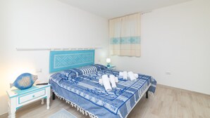 Un dormitorio con cama, mesita de noche, lámpara y un objeto con forma de pez sobre la mesita.
