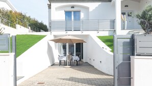 Un edificio blanco con un porche cubierto, una mesa con sillas y una verja.