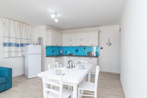A compact kitchen with white cabinets, a microwave, and a dining table with chairs.