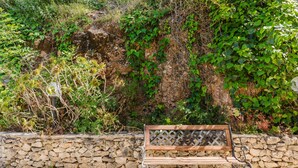 Un muro de piedra con un banco de madera al frente.