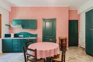 Une cuisine avec des armoires de couleur turquoise, un four à micro-ondes et une table recouverte d’une nappe rouge et blanche.