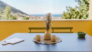 A table with a vase, two cups, and a placemat, set against a yellow wall with a view of a landscape. - Apartment 'Appartamento Superior Con Terrazza4' with Shared Pool, Wi-Fi and Air Conditioning (Castellammare del Golfo)