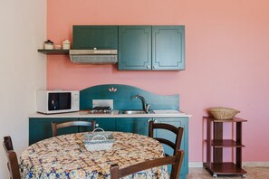 A kitchen with teal cabinets, a microwave, a sink, and a table with chairs.