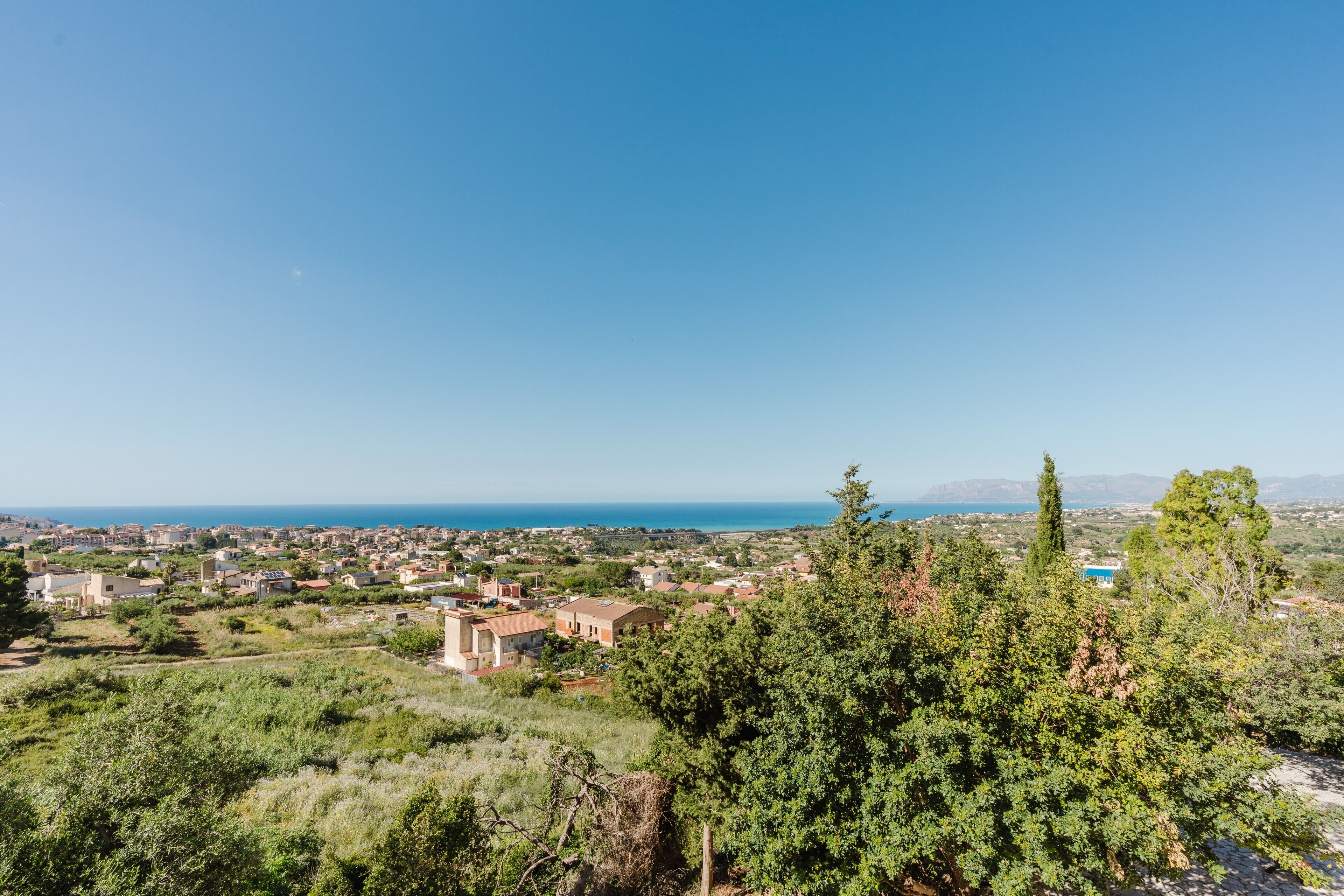Un pueblo costero con edificios, vegetación y una vista despejada del mar.