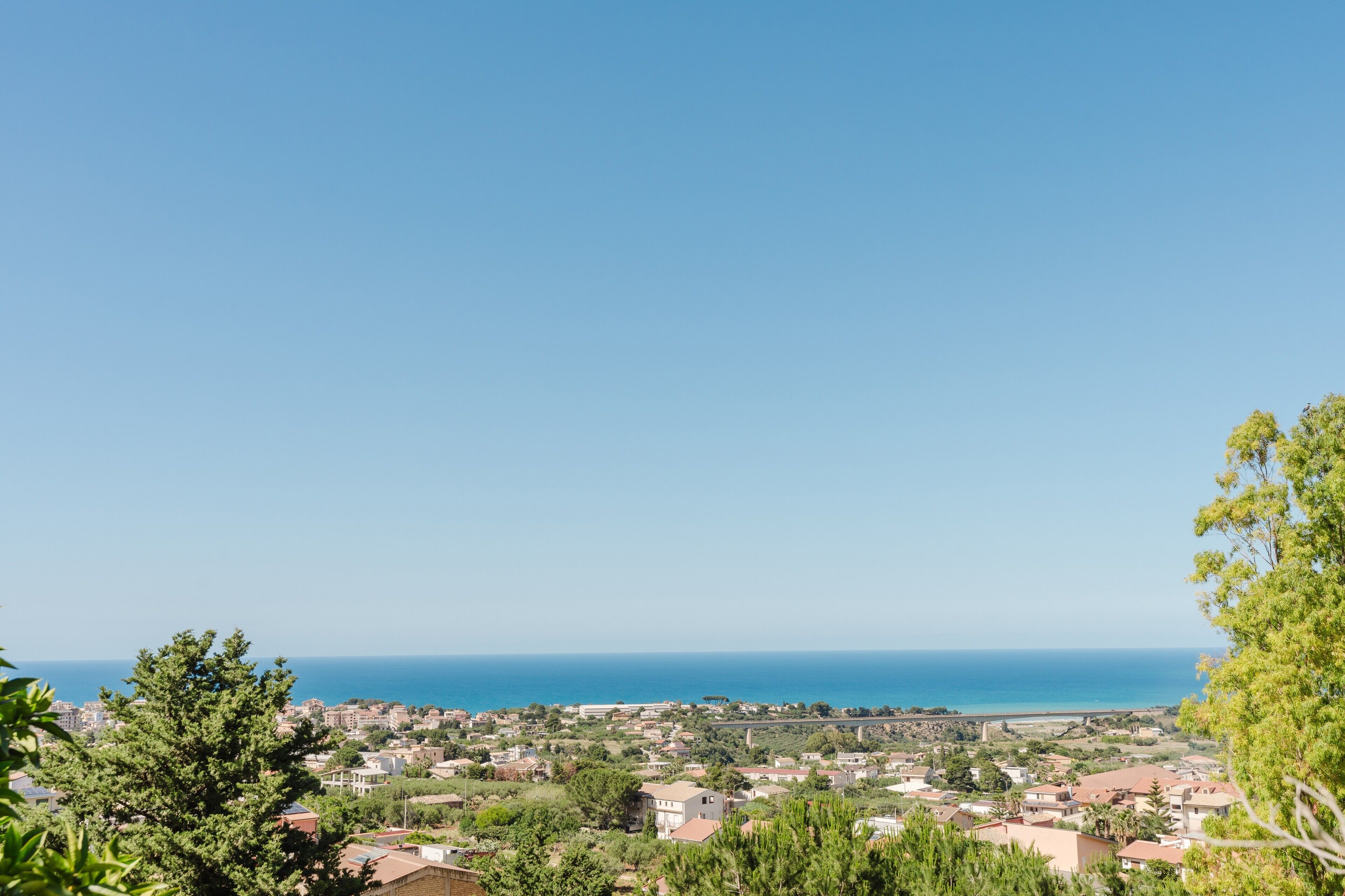 Une ville côtière avec des bâtiments, de la verdure et une vue dégagée sur la mer.