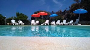 A swimming pool with white lounge chairs and umbrellas. - Apartment 'Appartamento Superior Con Terrazza5' with Shared Pool, Wi-Fi and Air Conditioning (Castellammare del Golfo)