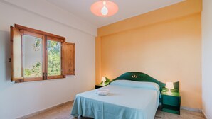 A bedroom with a bed, a nightstand, a lamp, a window with a view, and a ceiling light. - Apartment 'Appartamento Superior Con Balcone8' with Shared Pool, Wi-Fi and Air Conditioning (Castellammare del Golfo)