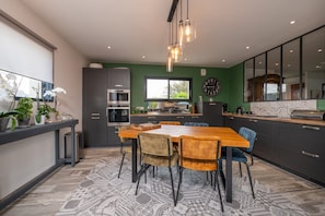 Une cuisine moderne avec une table à manger, des chaises et une grande fenêtre.