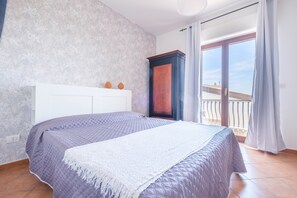 Une chambre à coucher comprenant un lit, une armoire, une fenêtre avec vue et un balcon.