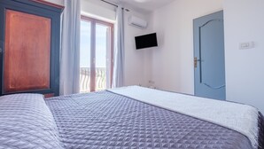 A bedroom with a large bed, a wardrobe, a television, and a door. - Apartment 'Medusa' with Balcony, Wi-Fi and Air Conditioning (Taormina)