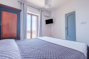 A bedroom with a large bed, a wardrobe, a television, and a door.