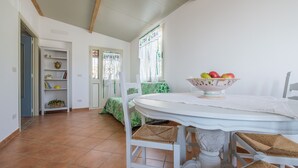 A dining area with a round table, white chairs, and a fruit bowl. - Apartment 'Medusa' with Balcony, Wi-Fi and Air Conditioning (Taormina)