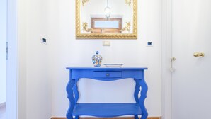 A blue console table with a drawer, a vase, and a mirror above it. - Apartment 'Medusa' with Balcony, Wi-Fi and Air Conditioning (Taormina)