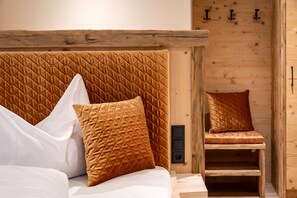 A wooden bed with a quilted headboard, a wooden chair, and a wall with a wooden panel.