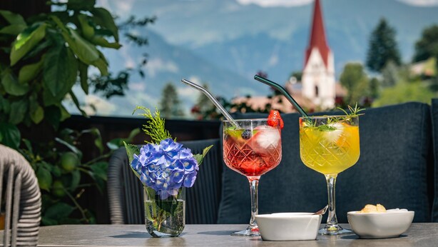 Une table avec deux boissons, un bol et un petit vase avec des fleurs.