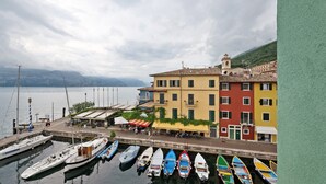 Un port de plaisance avec des bateaux amarrés, un bâtiment au bord de l’eau doté de balcons et une vue sur le lac.