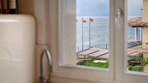 Une salle de bain avec un lavabo et une fenêtre donnant sur une étendue d’eau où flottent des drapeaux.