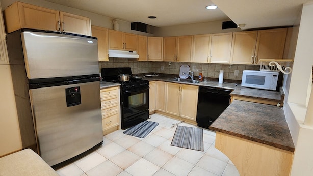 Una cocina compacta con refrigerador, estufa, microondas y armarios de madera.