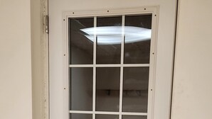 Una puerta blanca con un ventanal de diseño de cuadrícula y un timbre.