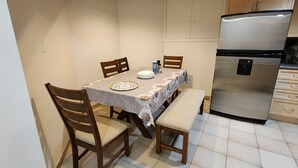Una cocina compacta con una mesa de comedor, sillas, un banco, un refrigerador y armarios.