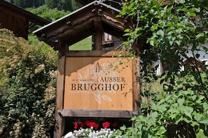 Un cartello di legno con la scritta 'A B BRUGGHOF' e un logo, immerso nel verde.