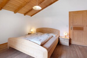 Un letto di legno con poggiatesta, comodini con lampade e una porta in legno.