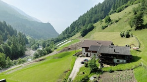 A rural house with a sloped roof, surrounded by green fields and a mountain backdrop. - Apartment 'Ausser Brugghof Birgit' with Mountain View, Shared Garden and Wi-Fi (Schnals)