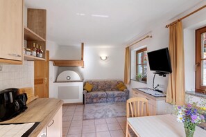 Una cucina funzionale con piano in legno, un divano, un tavolo da pranzo e una TV a parete.