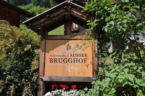 Un cartello di legno con la scritta 'A B BRUGGHOF' e un logo, immerso nel verde.