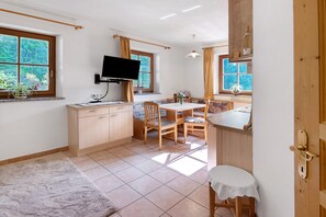 Una cucina con TV, mobili in legno, un tavolo da pranzo, sedie e una finestra con tende.
