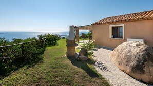 A house with a tiled roof, a stone pathway, and a view of the sea.