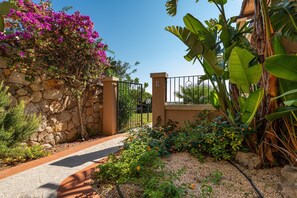 A stone wall, a metal gate, and a pathway leading to a building.
