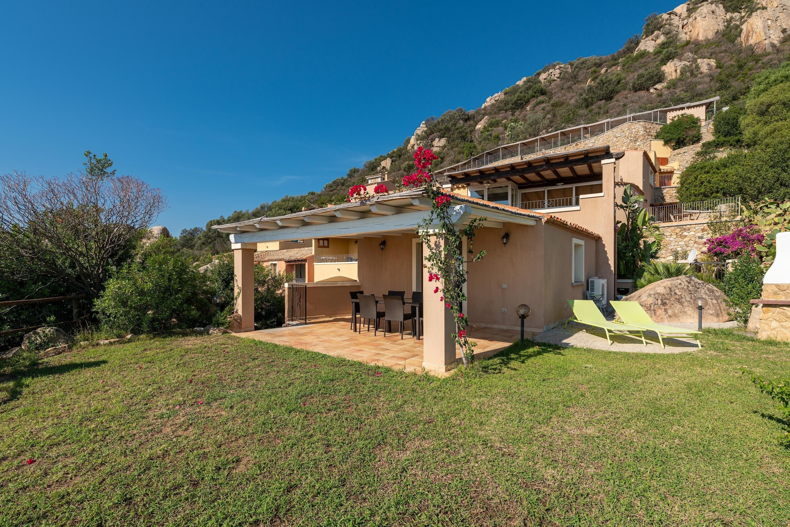 A villa with a patio, outdoor seating, and a view of a mountainous landscape.