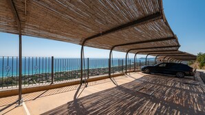 A covered outdoor area with a car parked, overlooking a coastal view.